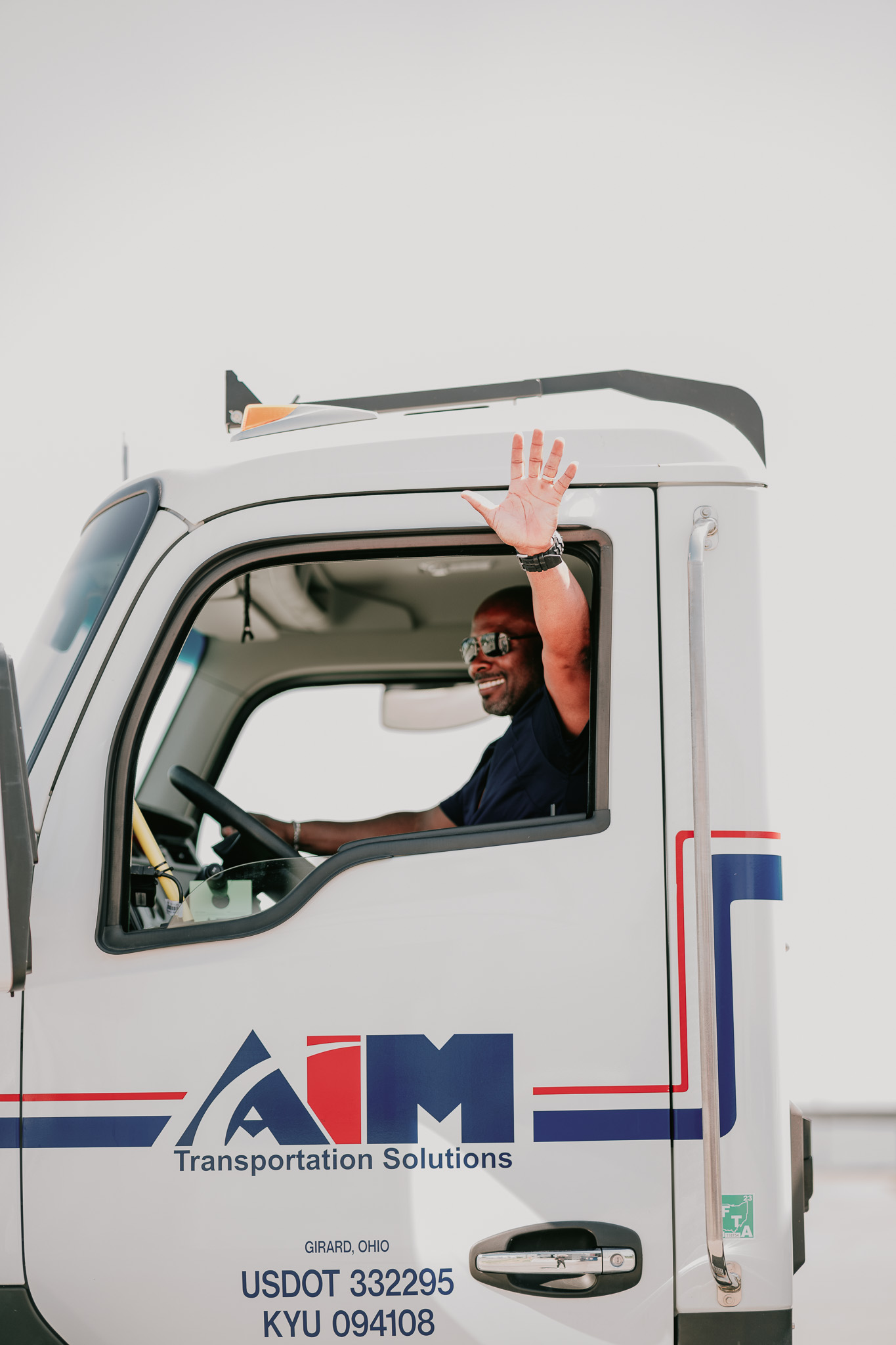 Picture of an Aim driver waving from the cab of his truck.
