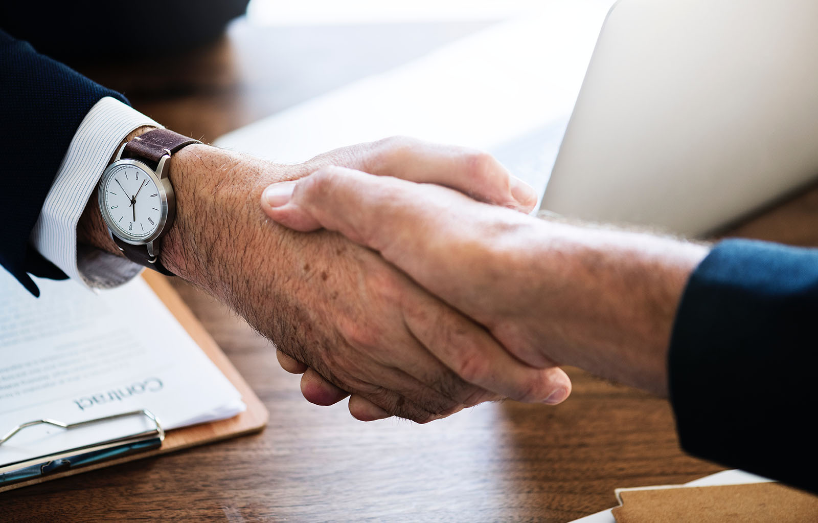 A close-up shot of two mens' hands shaking in a business deal.