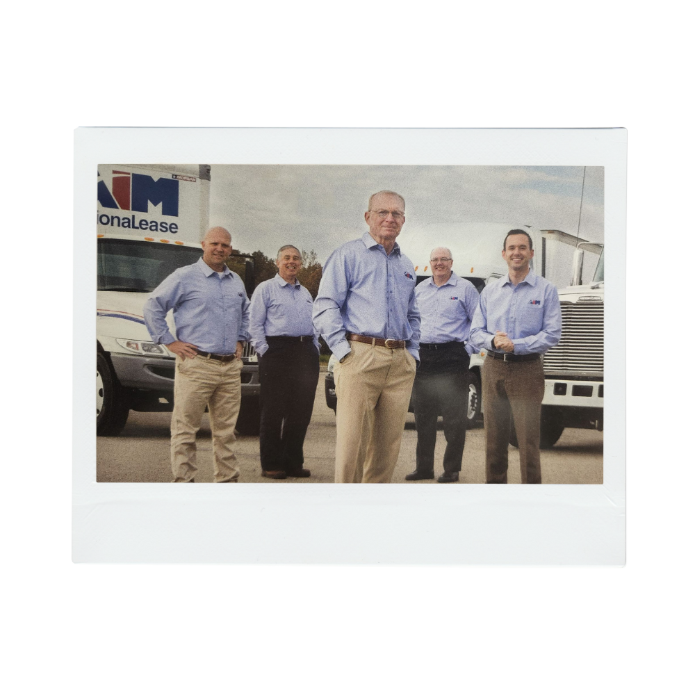 Various members from the Aim administrative team standing in a parking lot with Aim trucks behind them.