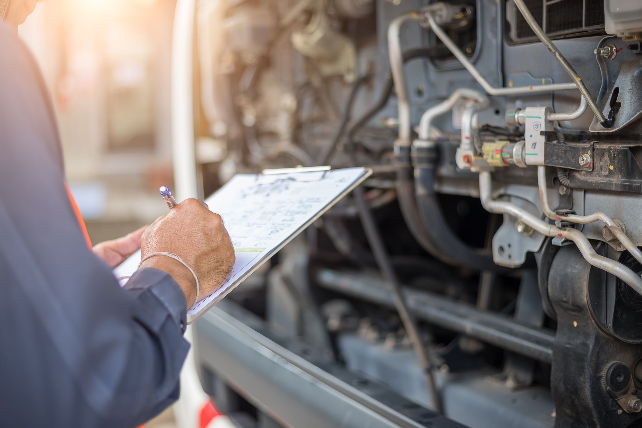 Inspector conducting a check with exposed truck parts in the background