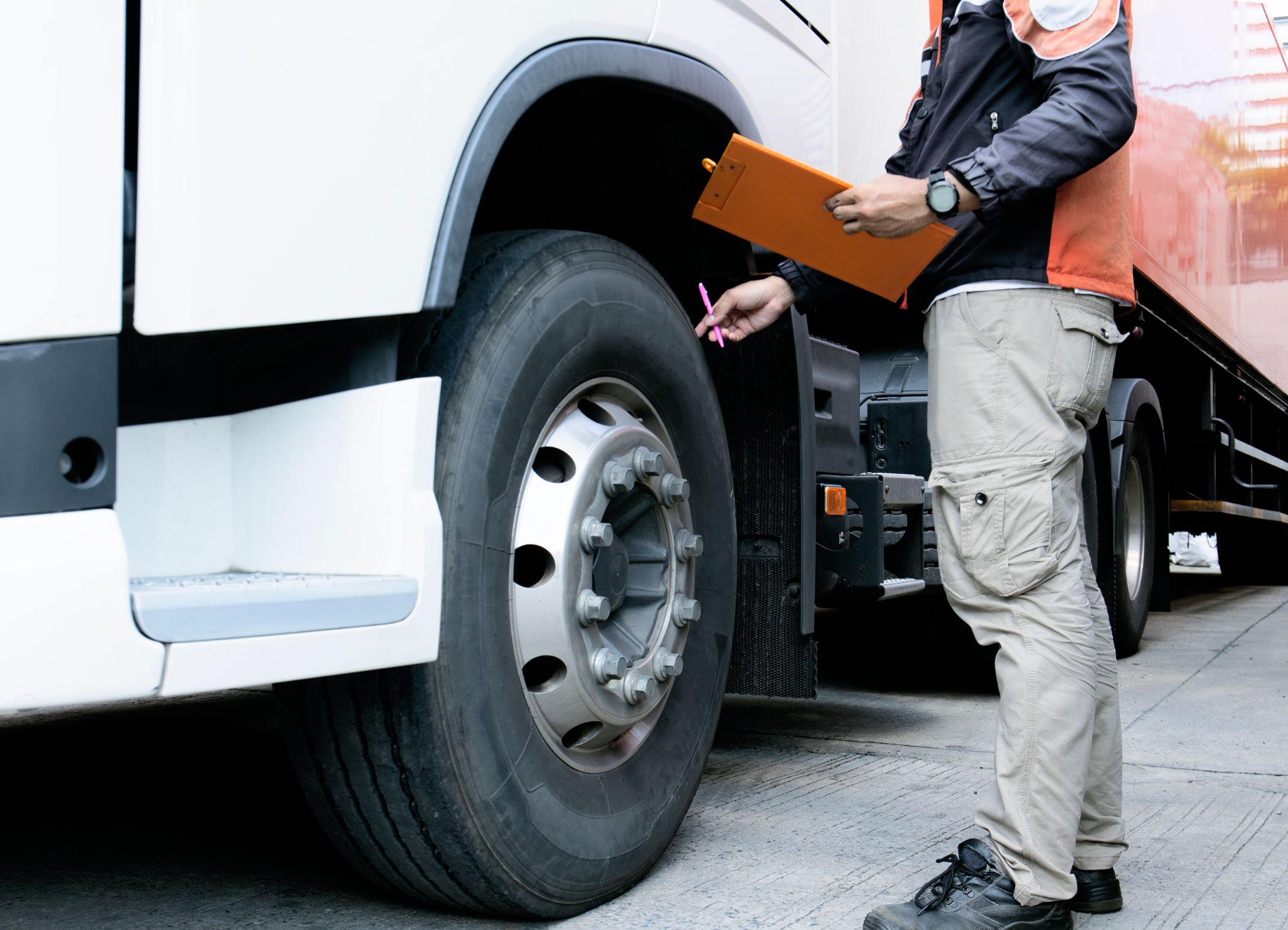 Inspector conducting a check in an orange vest inspecting tires